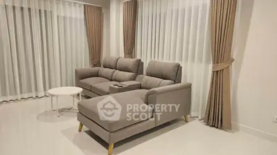 Spacious living room with elegant gray sofa and chic curtains, perfect for modern living.