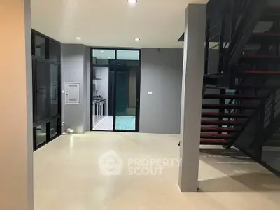 Modern open-plan interior with sleek staircase and large windows