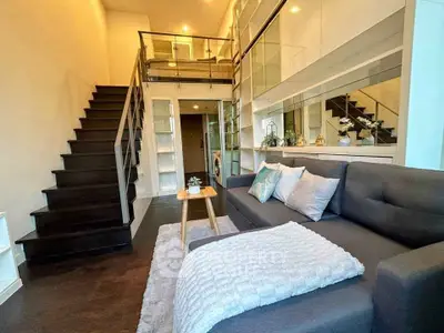 Modern duplex living room with stylish staircase and cozy seating area.