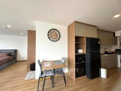 Modern open-plan living space with kitchen and dining area, featuring stylish decor and wooden flooring.