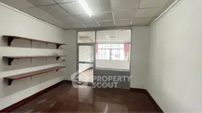 Spacious room with wooden shelves and large window, ideal for home office or study area.