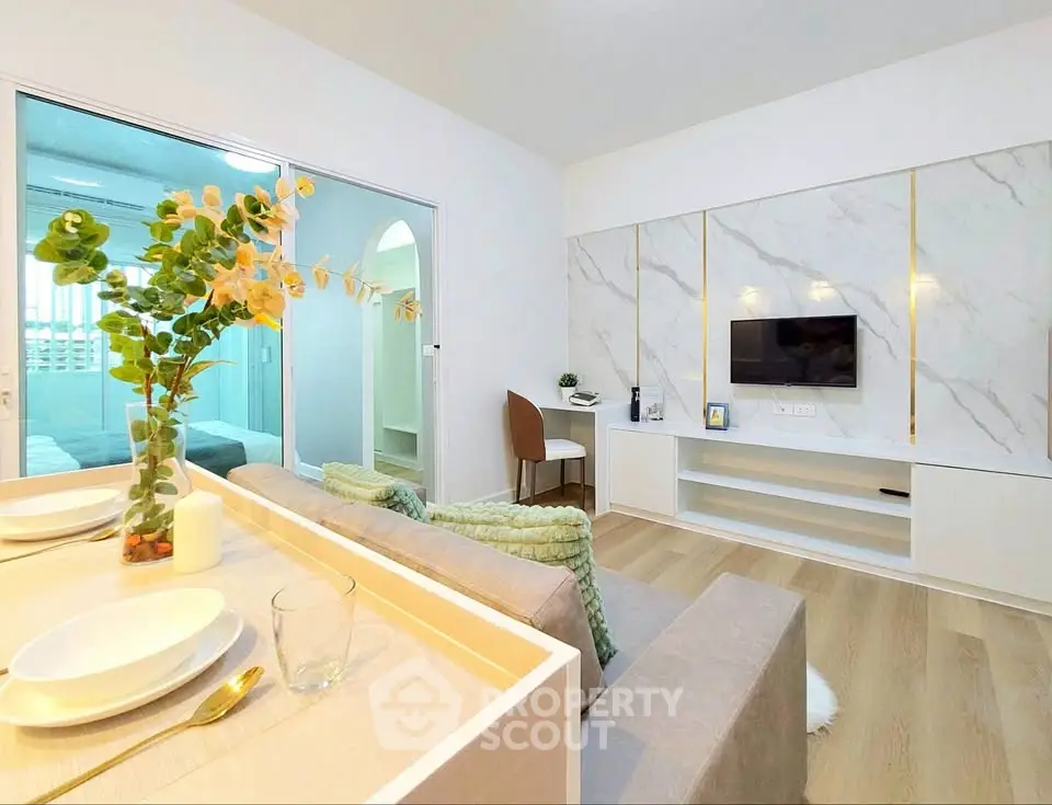 Modern living room with stylish decor and open layout, featuring a cozy sofa and wall-mounted TV.