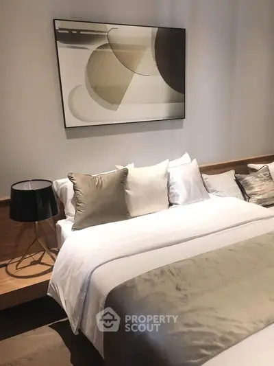 Luxurious bedroom with modern art and elegant bedding, perfect for a serene retreat.