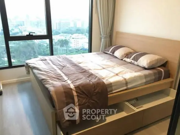 Modern bedroom with large window offering stunning city views and ample natural light.