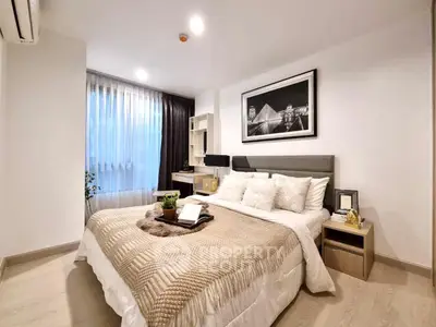 Elegant bedroom with cozy bedding and modern decor, featuring a stylish desk and large window for natural light.