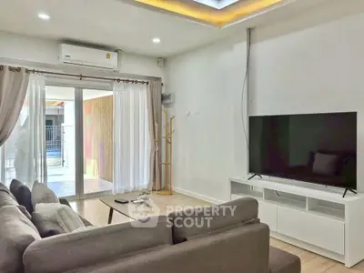 Modern living room with large TV and sliding glass doors to balcony