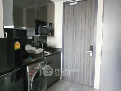 Modern kitchen with sleek appliances and washing machine in compact space.