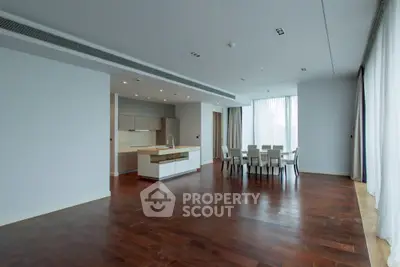 Spacious modern living room with open kitchen and dining area, featuring elegant hardwood floors.