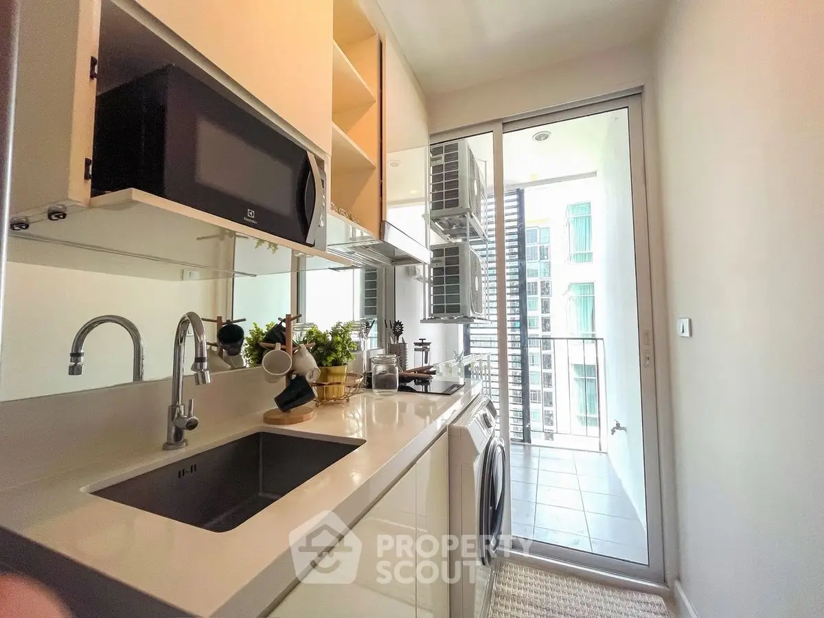 Modern kitchen with sleek appliances and balcony view in urban apartment