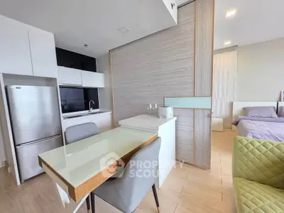 Modern open-plan kitchen and dining area with sleek design and cozy bedroom view.