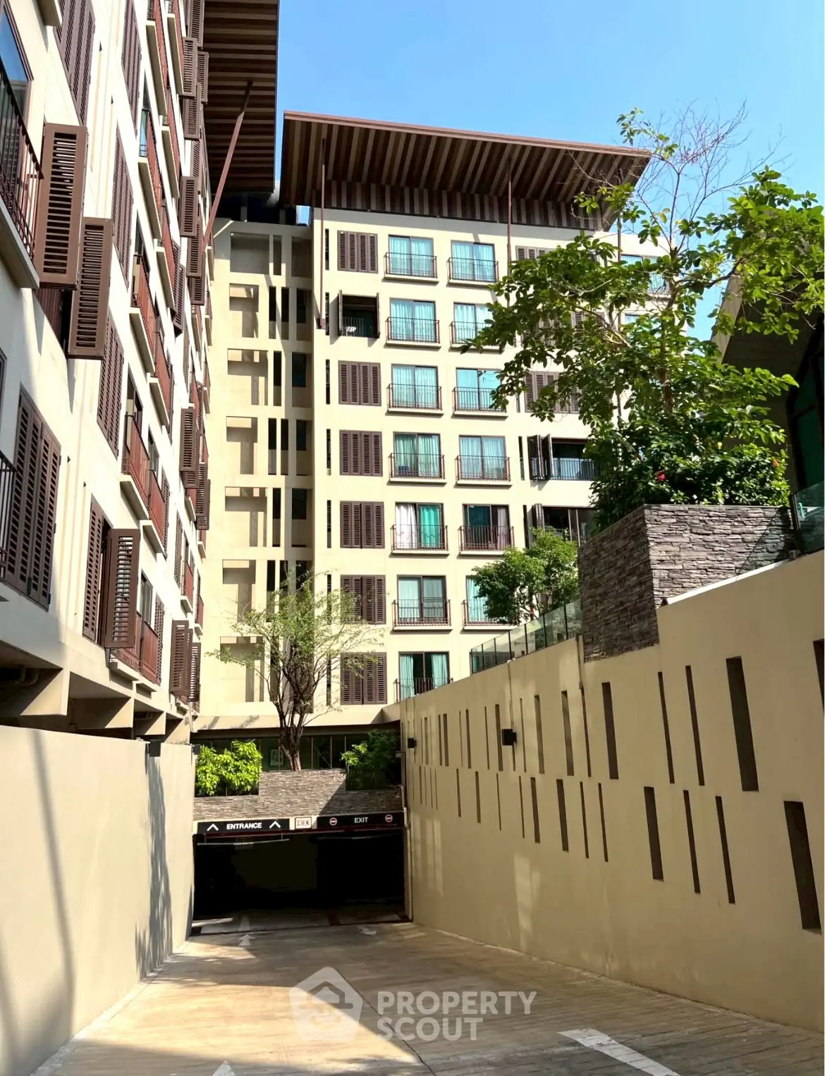 Modern apartment building exterior with lush greenery and parking entrance