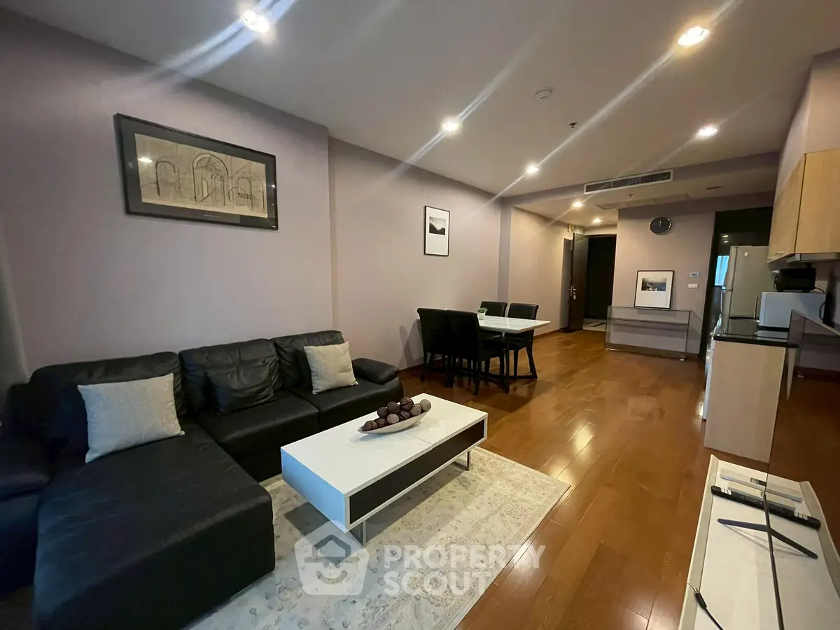 Spacious modern living room with sleek furniture and open kitchen layout.