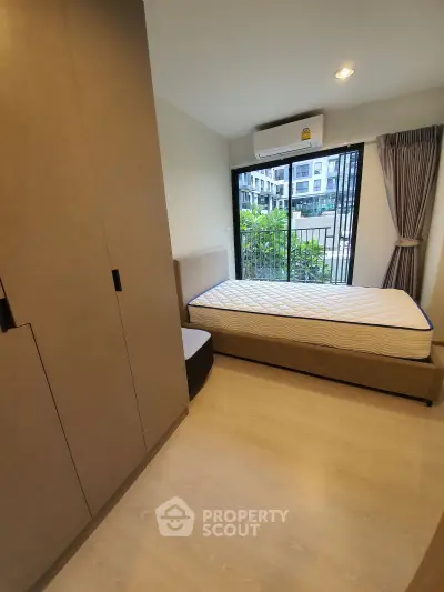 Modern bedroom with large window and built-in wardrobe in urban apartment