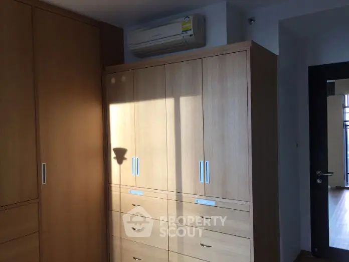 Spacious bedroom with built-in wooden wardrobes and air conditioning unit.