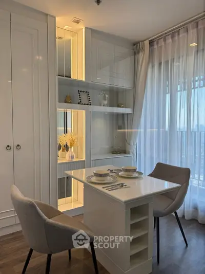 Modern dining area with elegant table and chairs, featuring built-in shelving and large windows for natural light.