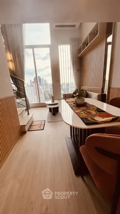 Modern living room with high ceilings and city view, featuring stylish decor and natural light.