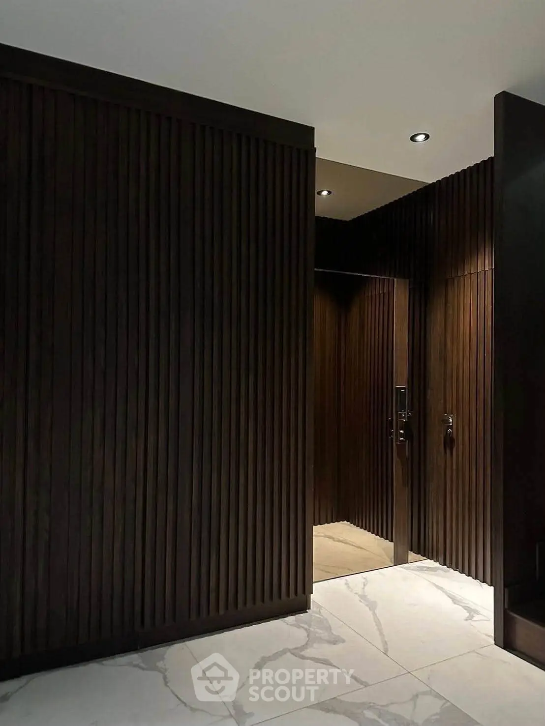 Elegant modern entrance with dark wood paneling and marble flooring