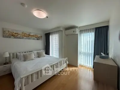 Spacious bedroom with modern decor and natural light in a stylish apartment.