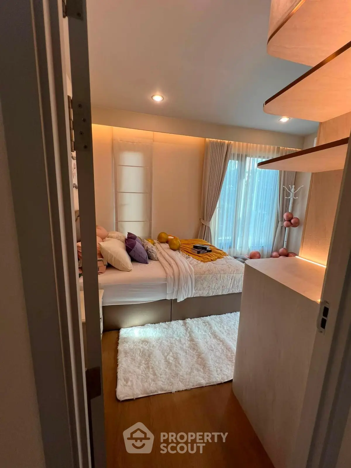 Cozy bedroom with modern decor and natural light, featuring a plush bed and stylish shelving.