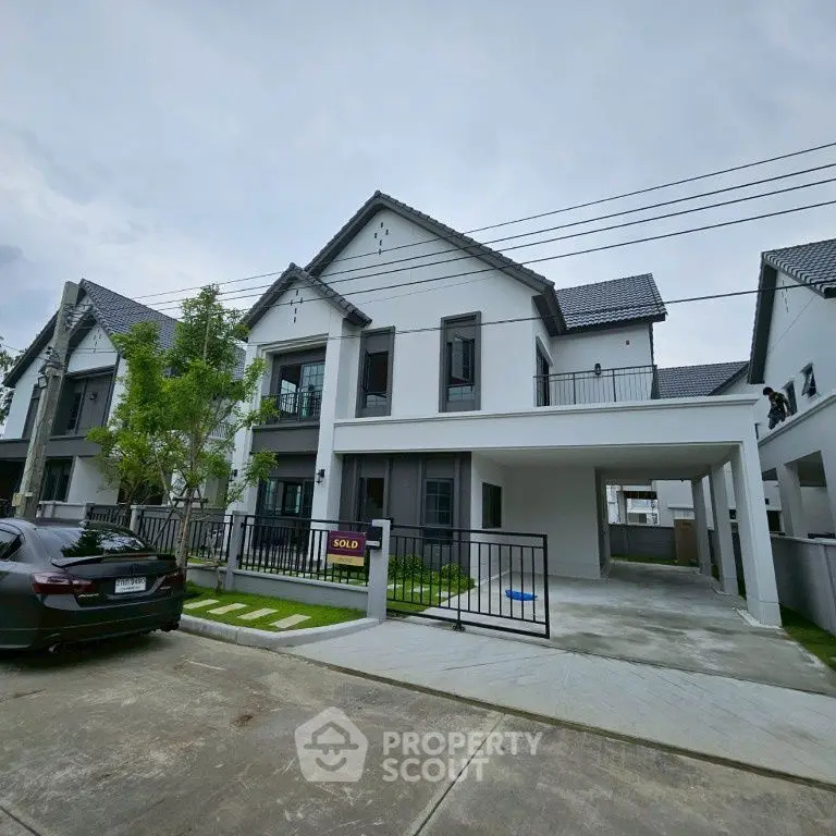 Modern townhouse with sold sign, featuring sleek design and spacious driveway in a serene neighborhood.