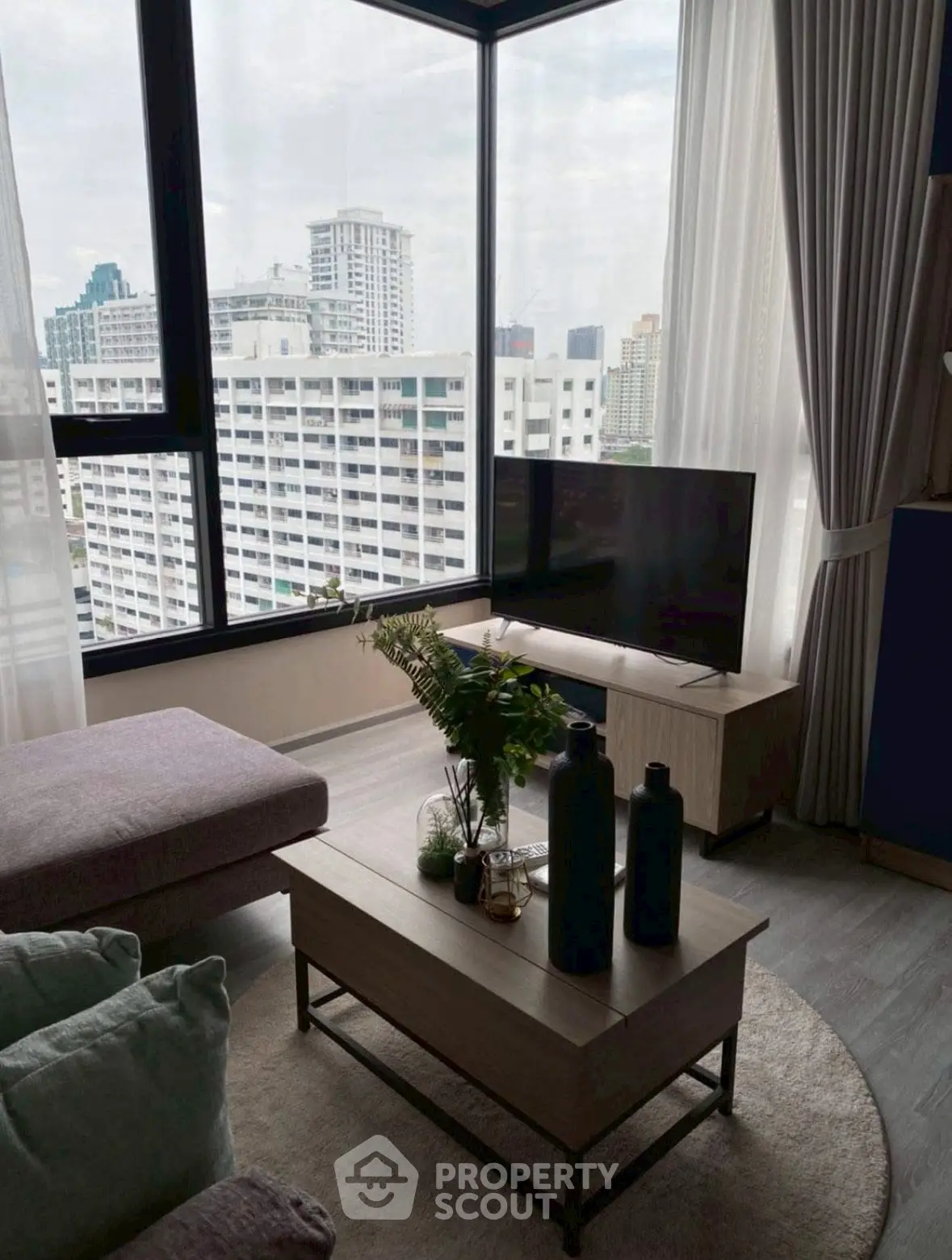 Modern living room with panoramic city view, stylish furniture, and natural light.