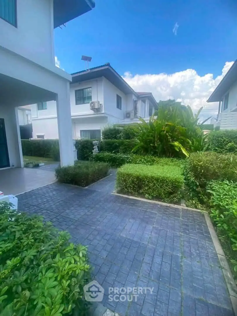Charming suburban home with lush garden and paved walkway, perfect for family living.