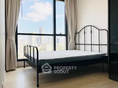 Bright bedroom with large window offering stunning city views, featuring a stylish metal bed frame and elegant curtains.
