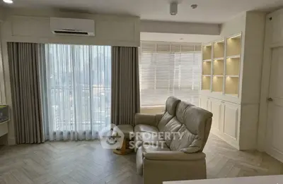 Elegant living room with natural light, featuring a cozy leather sofa and built-in shelving.