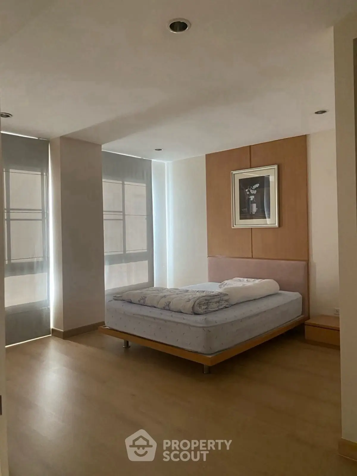 Spacious bedroom with modern decor and large windows for natural light.