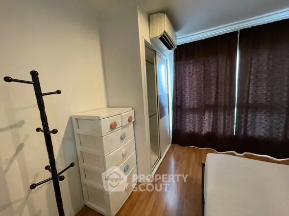 Cozy bedroom with wooden flooring, mirrored closet, and air conditioning unit.