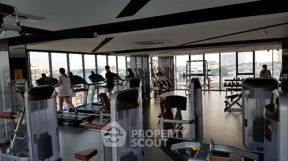 Spacious gym with modern equipment and panoramic city views, perfect for fitness enthusiasts.
