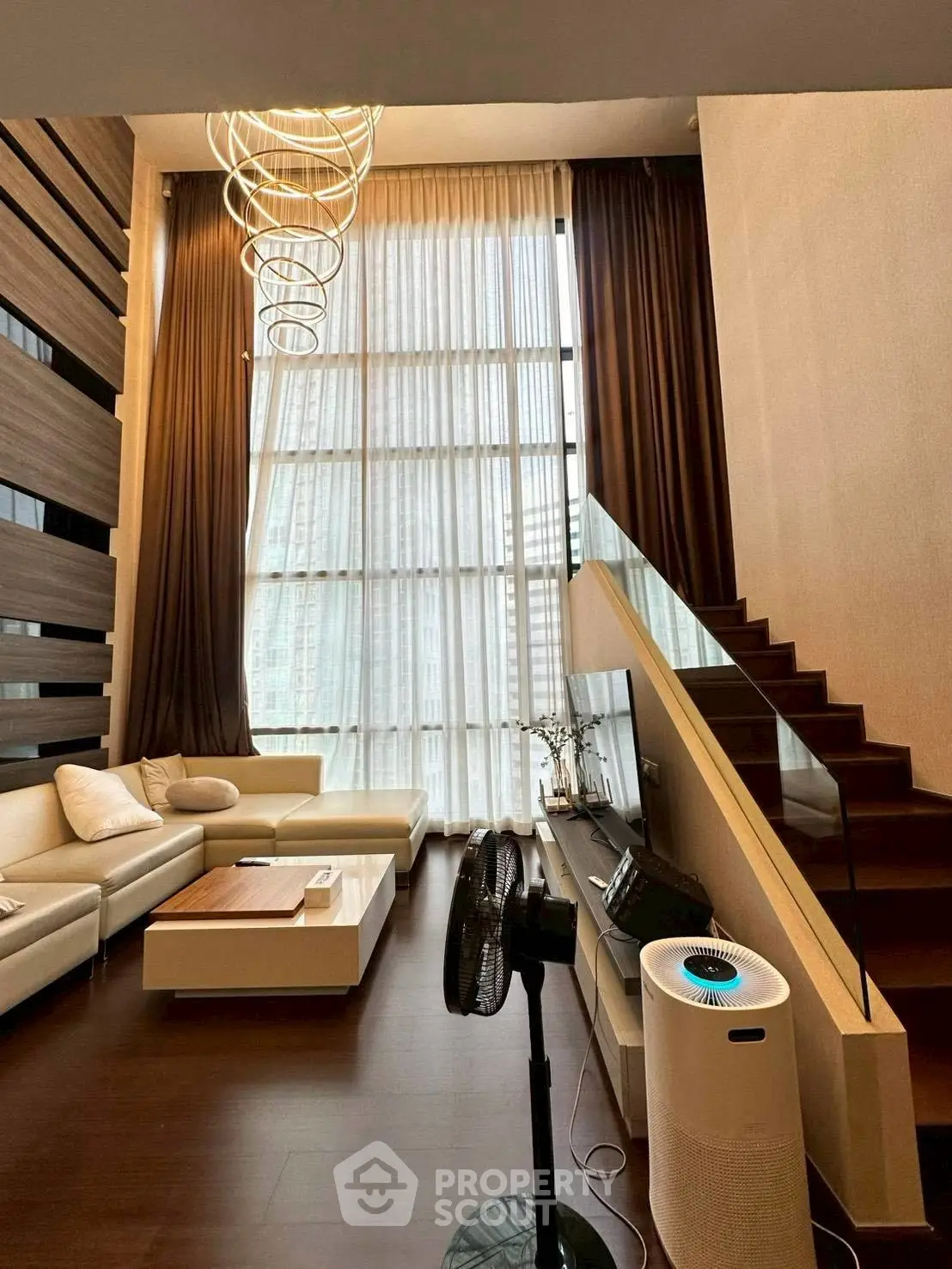Luxurious modern living room with high ceilings and elegant staircase in a stylish apartment.