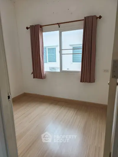 Cozy small bedroom with wooden flooring and window view
