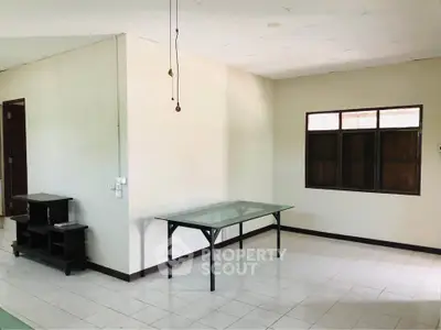 Spacious unfurnished room with tiled floor and large window, ideal for customization.