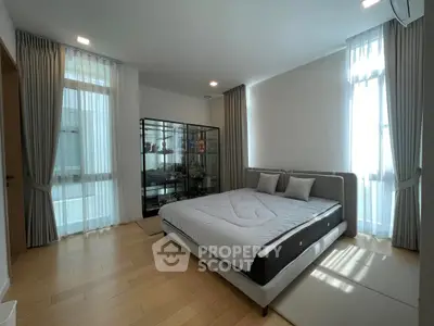 Spacious bedroom with modern decor and large windows for natural light.