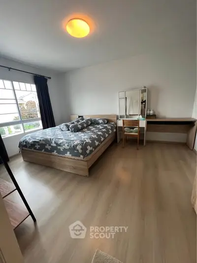 Spacious bedroom with modern decor and large window for natural light