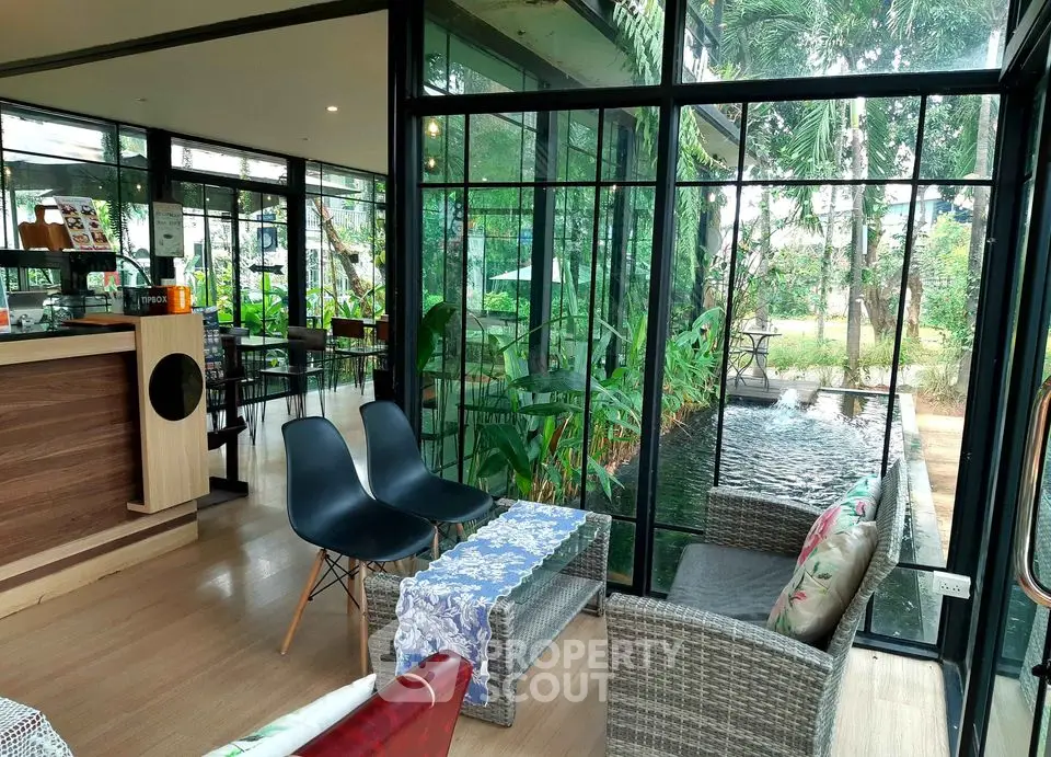 Modern glass-walled living area with garden view and stylish furniture