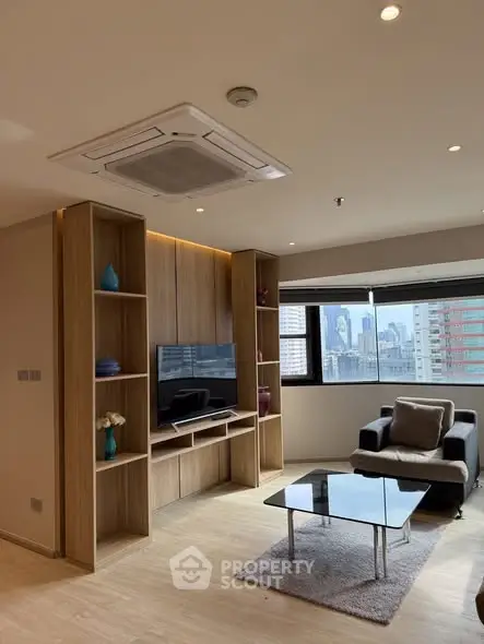 Modern living room with city view, sleek furniture, and built-in TV unit.