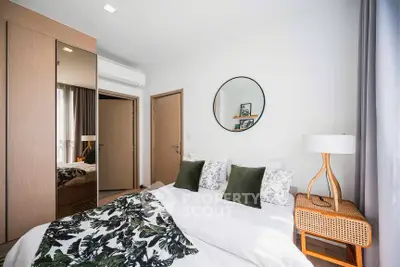 Cozy bedroom with modern decor, featuring a stylish mirror and elegant lighting.