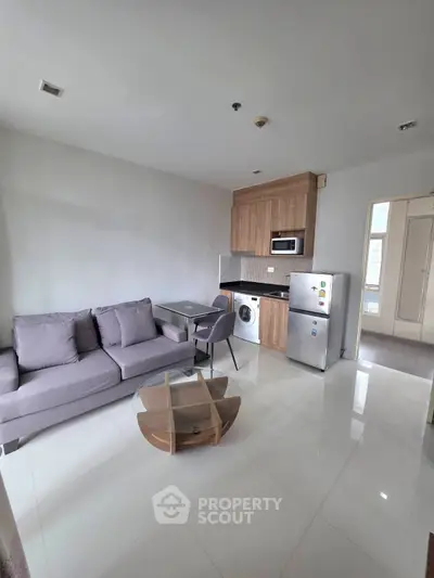 Modern living room with sleek kitchen, featuring washing machine and fridge, perfect for urban living.