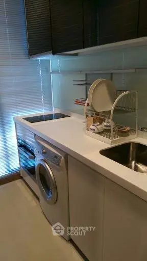 Modern kitchen with sleek design featuring washing machine and electric stove