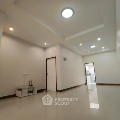 Spacious and modern living room with recessed lighting and sleek tile flooring.