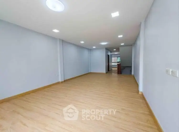 Spacious empty room with wooden flooring and recessed lighting, ideal for customization.