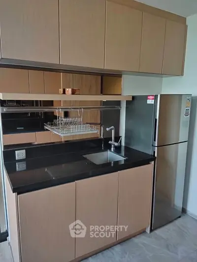 Modern kitchen with sleek cabinetry and stainless steel fridge in a contemporary apartment.