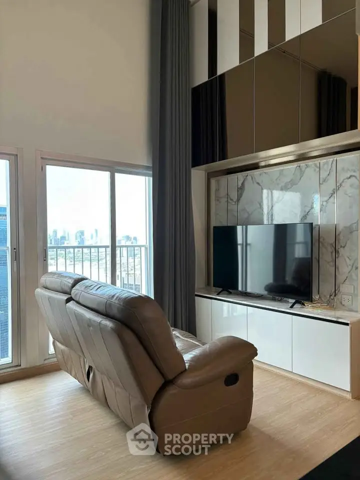 Modern living room with city view, featuring sleek TV setup and cozy leather sofa.