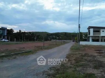 Spacious plot of land with scenic views and modern house nearby, ideal for development.