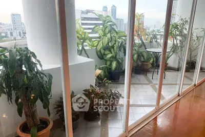 Spacious balcony with lush greenery and city view, perfect for relaxation and outdoor dining.