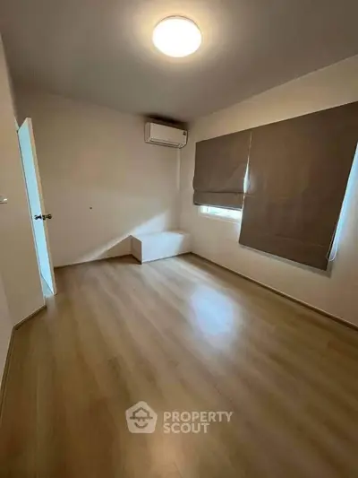 Spacious unfurnished bedroom with wooden flooring and air conditioning, perfect for customization.