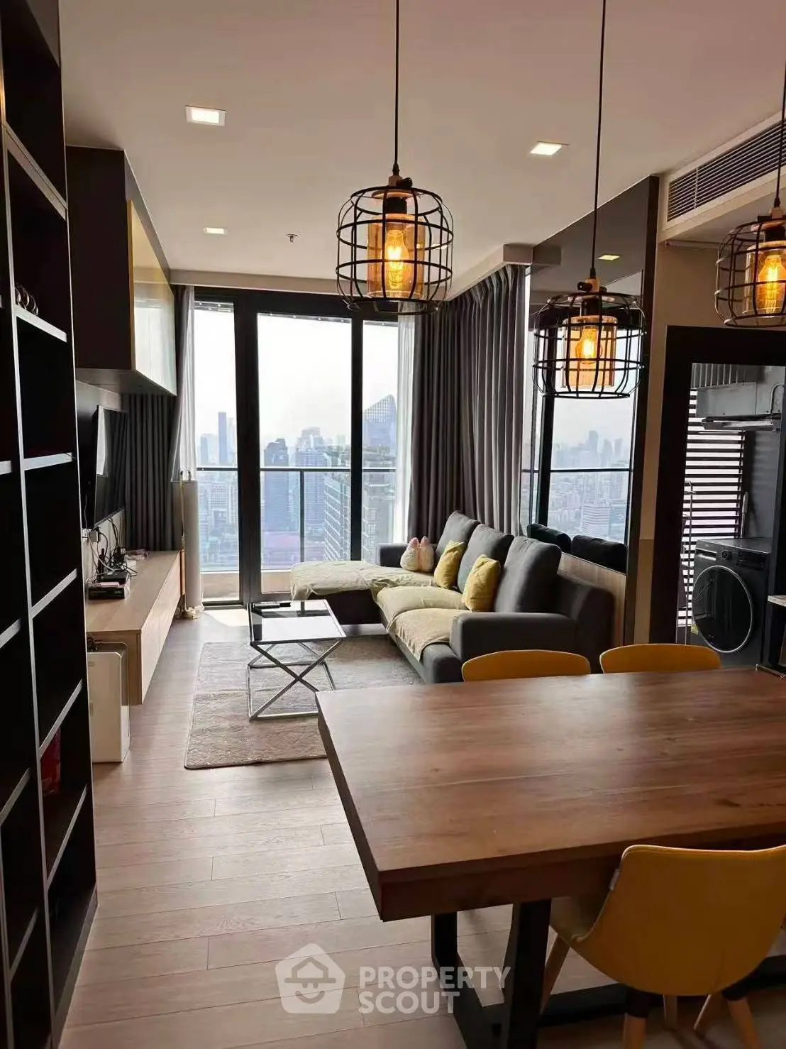 Modern living room with city view, stylish lighting, and cozy seating area in a high-rise apartment.