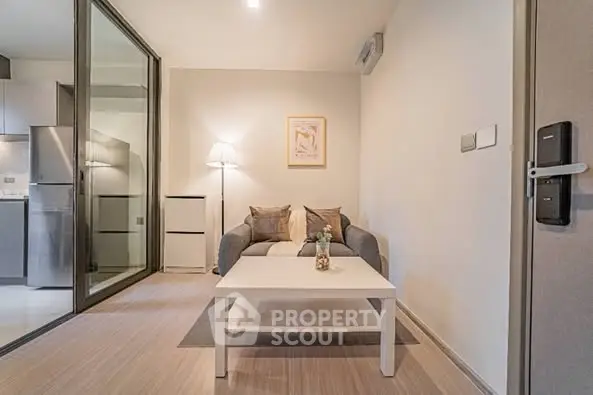 Modern living room with cozy sofa and stylish decor adjacent to sleek kitchen area.